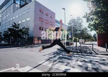 Aufgeregt junge Frau springen auf der Stadtstraße während sonnigen Tag Stockfoto