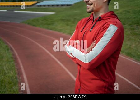 Junger, fröhlicher persönlicher Fitnesstrainer auf der Laufstrecke Stockfoto