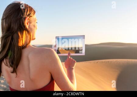 Frau, die ein Bild mit Tablet bei Sonnenuntergang in den Dünen, Gran Canaria, Spanien Stockfoto