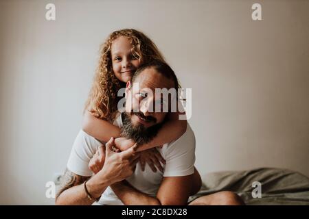 Vater Huckepack Tochter auf Bett zu Hause Stockfoto