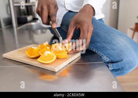 Die Hände des Mannes schneiden orange, Nahaufnahme Stockfoto