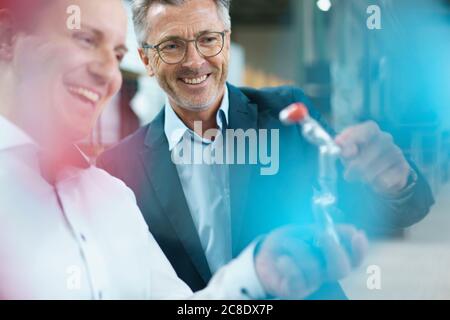 Zwei glückliche Geschäftsleute halten Produkt in einer Fabrik Stockfoto