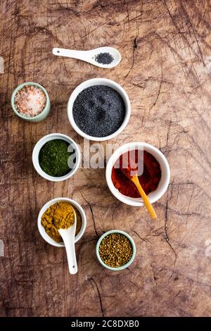 Schüsseln mit Mohn, rosa Salz, Currypulver, getrocknetem Thymian, Koriandersamen, rotem Paprika Stockfoto