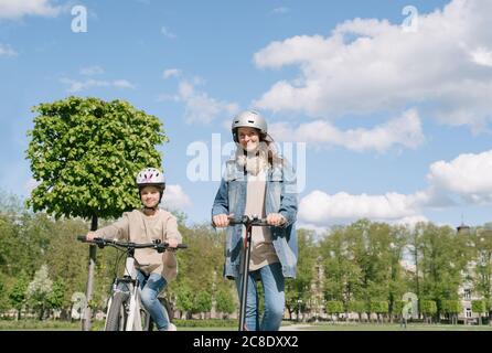 Mädchen Radfahren, während Mutter Motorrad gegen Himmel in der Stadt reiten parken Stockfoto