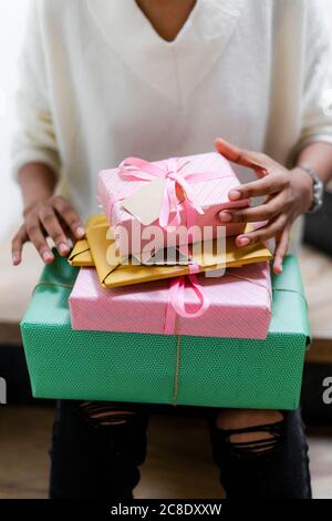 Junge Frau mit Stapel von verpackten Geschenken Stockfoto