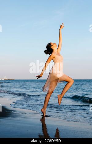 Zarte Ballerina tanzen am Strand bei Sonnenuntergang Stockfoto