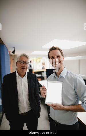 Zwei erfolgreiche Geschäftsleute stehen im Büro, mit digitalen Tablet Stockfoto