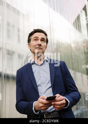 Reifer Geschäftsmann mit Smartphone in der Stadt Stockfoto