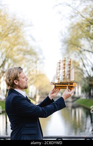 Geschäftsmann hält Modellschiff an einem Kanal Stockfoto