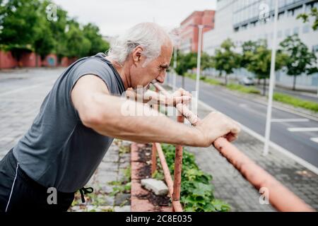 Älterer Mann, der in der Stadt Geländer trainiert Stockfoto