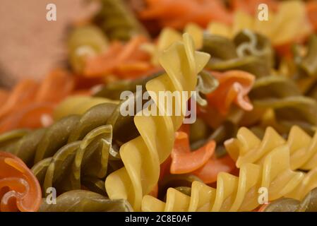 Zusammensetzung von rohen Pasta ungekocht tricolore fusilli, Pasta Twist Form. Nahaufnahme und selektiver Fokus auf bunte Fusilli Pasta. Teigwaren in verdrehten Farben Stockfoto