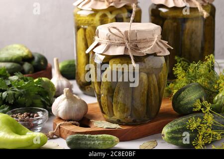 Marinierte Gurken mit Knoblauch, Pfeffer und Dill in Gläsern auf hellgrauem Hintergrund, Horizontalformat, Closeup Stockfoto