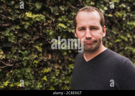 Nahaufnahme eines mittleren erwachsenen Mannes, der Gesicht gegen Pflanzen in macht parken Stockfoto