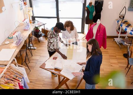 Modedesignerin mit jungen Auszubildenden, die im Atelier unterrichten Stockfoto