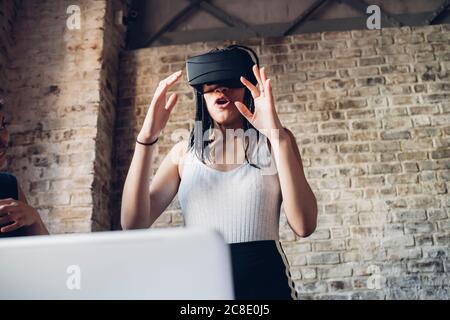 Aufgeregt junge Frau trägt VR-Brille im Loft-Büro Stockfoto