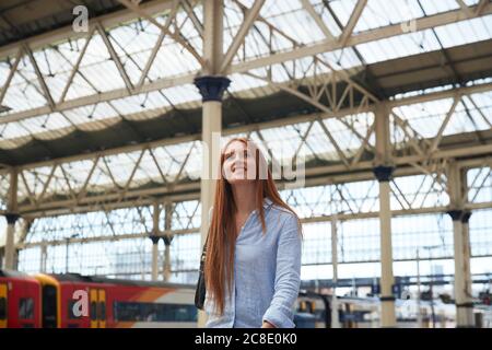 Nachdenkliche junge Frau, die am Bahnhof läuft Stockfoto