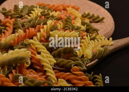 Zusammensetzung von rohen Pasta ungekocht tricolore fusilli, Pasta Twist Form. Nahaufnahme und selektiver Fokus auf bunte Fusilli Pasta. Teigwaren in verdrehten Farben Stockfoto