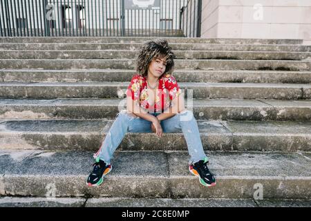 Trendige junge Frau sitzt auf der Treppe Stockfoto