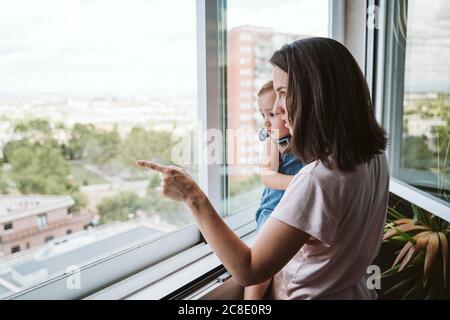 Mutter mit Baby Mädchen zu Hause Blick am Fenster Stockfoto