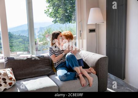 Mutter küsst niedlichen Sohn während sitzen auf Sofa im Leben Zimmer zu Hause Stockfoto