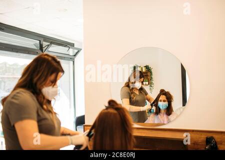 Weiblicher Friseur mit Maske mit Richtmaschine Stockfoto