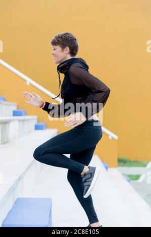 Lächelnde athletische Frau, die auf Treppen läuft Stockfoto