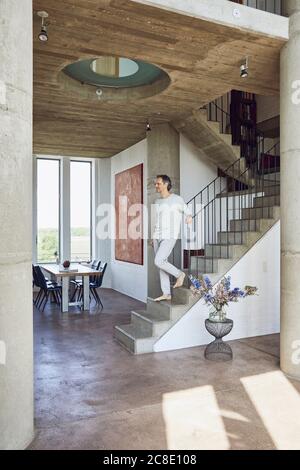 Älterer Mann, der in einer Loft-Wohnung die Treppe hinunter ging Stockfoto