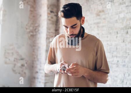 Stilvoller junger Mann mit Smartphone im Loft Stockfoto