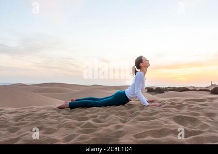 Frau praktiziert Yoga bei Sonnenuntergang in den Dünen, Gran Canaria, Spanien Stockfoto