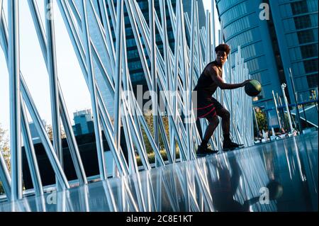 Junger Mann spielt Basketball in der modernen Umgebung der Stadt Stockfoto