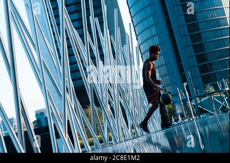 Junger Mann spielt Basketball in der modernen Umgebung der Stadt Stockfoto