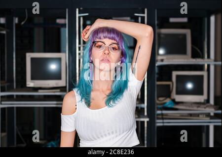 Trendy blauhaarige weibliche Gamer stehen mit Arm angehoben Zu Hause Stockfoto