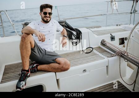 Lächelnder junger Mann mit Sonnenbrille im Segelboot Stockfoto
