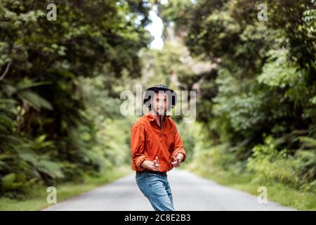 Selbstbewusster junger Mann, der im Wald auf der Straße steht Stockfoto