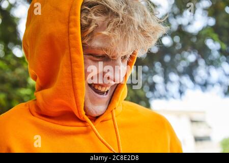 Porträt eines lachenden jungen Mannes mit orangefarbenem Kapuzenpullover Stockfoto