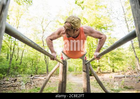 Reifer Mann tut Liegestütze auf parallelen Bars im Park Stockfoto