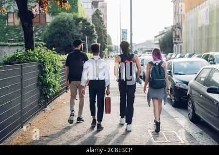 Eine Gruppe von Freunden, die auf dem Bürgersteig in der Stadt spazieren Stockfoto