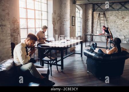 Kreatives Team im Loft-Büro mit technologischen Geräten Stockfoto