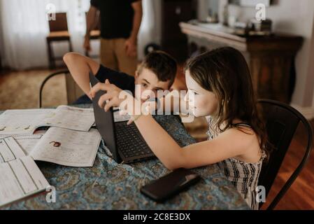 Geschwister studieren über Laptop zu Hause während der Ausgangssperre Stockfoto