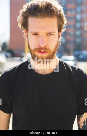 Nahaufnahme eines bärtigen, hübschen Mannes, der bei Sonnenschein in der Stadt steht Tag Stockfoto