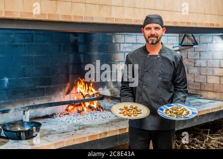 Traditionelle Küche im Restaurant ktischen, Koch zeigt Teller mit gegrillten Meeresfrüchten Stockfoto