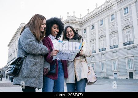 Weibliche Touristen analysieren Karte, während sie gegen den Königspalast von Madrid, Spanien, stehen Stockfoto