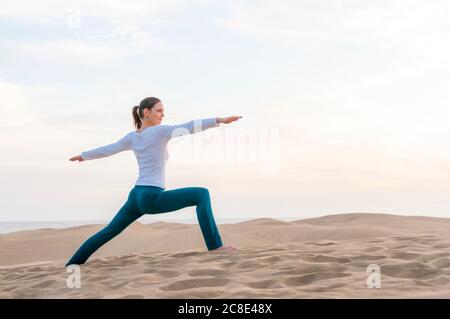 Frau praktiziert Yoga bei Sonnenuntergang in den Dünen, Gran Canaria, Spanien Stockfoto