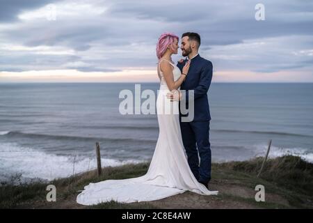 Brautpaar am Aussichtspunkt und Meer im Hintergrund Stockfoto