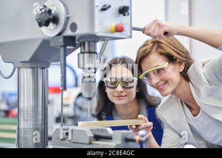 Weibliche Managerin beim Bohren von Metall während der Ausbildung Arbeiter in der Metallindustrie Stockfoto