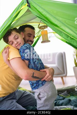 Vater umarmt seinen Sohn im Zelt zu Hause Stockfoto