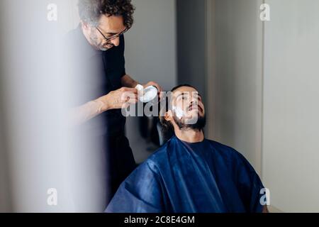 Friseur Anwendung Rasiercreme auf Client im Salon Stockfoto