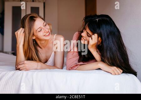 Freunde, die einander anguckt, während sie auf dem Bett liegen Zu Hause Stockfoto