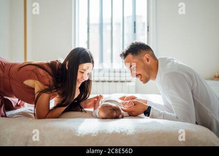 Glückliche Eltern spielen mit Baby Junge im Schlafzimmer zu Hause Stockfoto