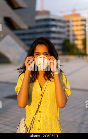 Junge Frau trägt Gesichtsmaske, während sie in der Stadt steht Stockfoto